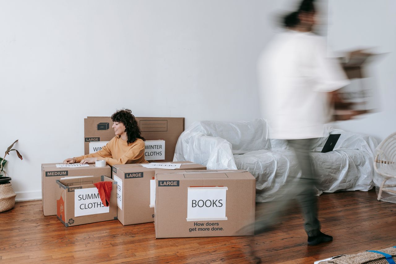 A couple packing marked boxes in a clean, minimalist living room as they get ready for moving day.